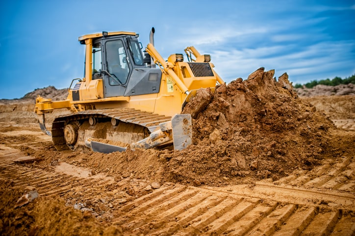 yellow bulldozer moving dirt at a job site